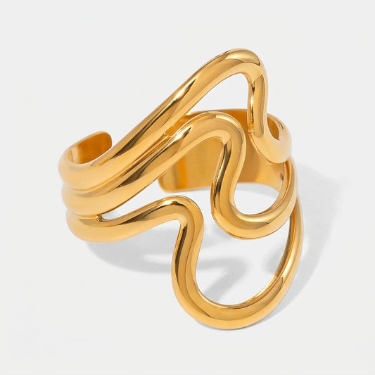 Gold ring with wavy design on a light gray background