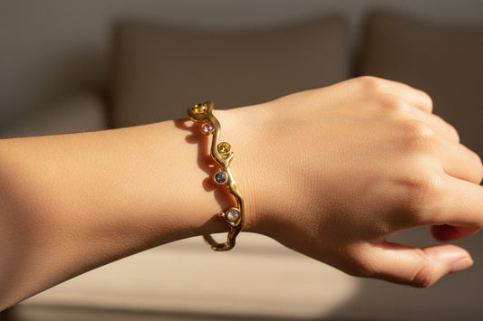 Gold bracelet with colorful gemstones on a white background